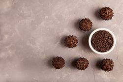 Top view of chocolate truffles with sprinkles on marble surface with space for text