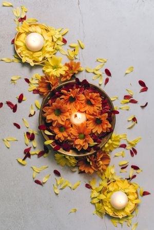 Top view of orange and yellow flower petals in bowls with candles