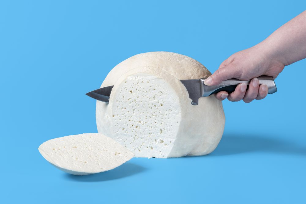 Woman hand slicing cheese with a knife