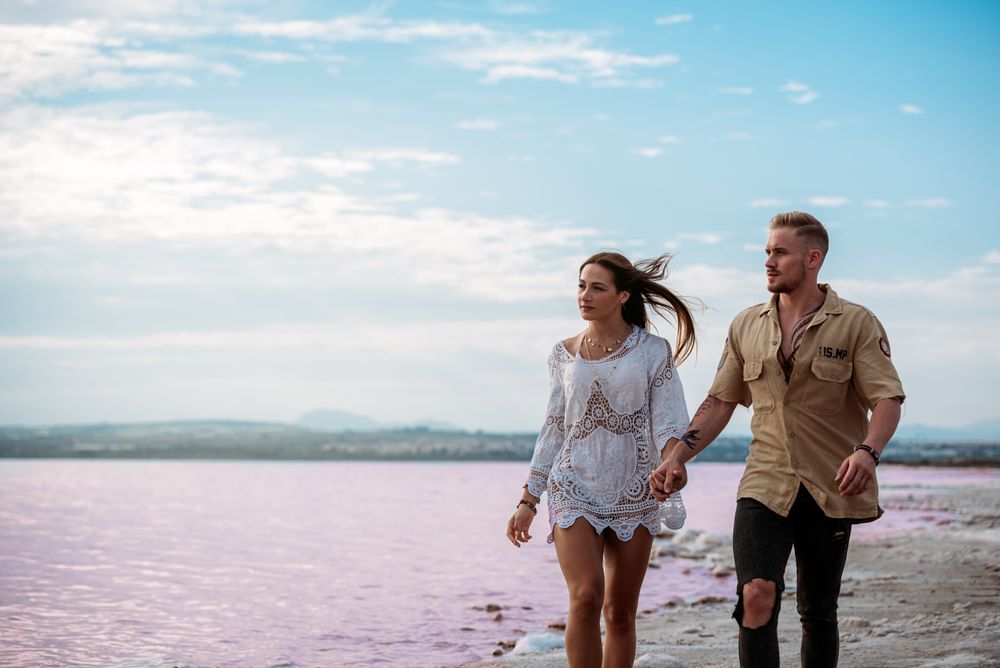 adorable couple walking on an amazing beach with pink water