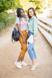 Female friends posing together in casual clothing in park walk way