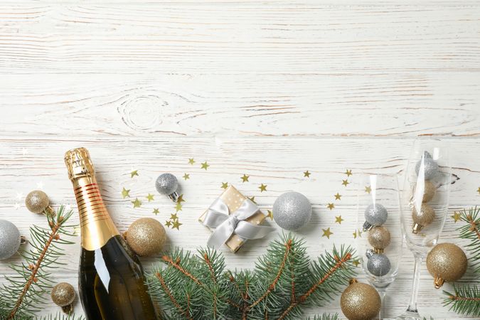 Concept with christmas baubles and champagne on light wooden background, copy space
