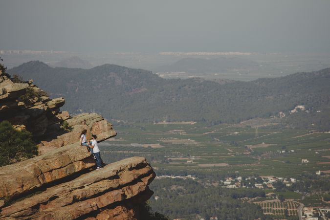 Distant loving couple standing on high cliff