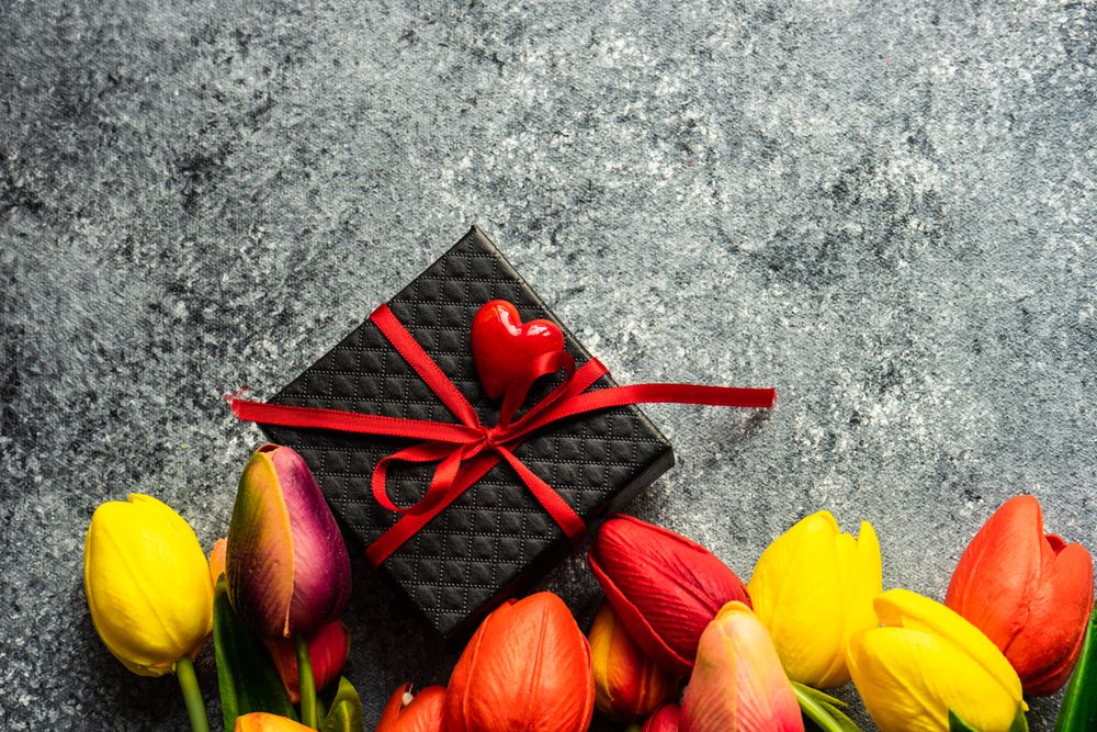 Fresh tulips on grey counter with giftbox 