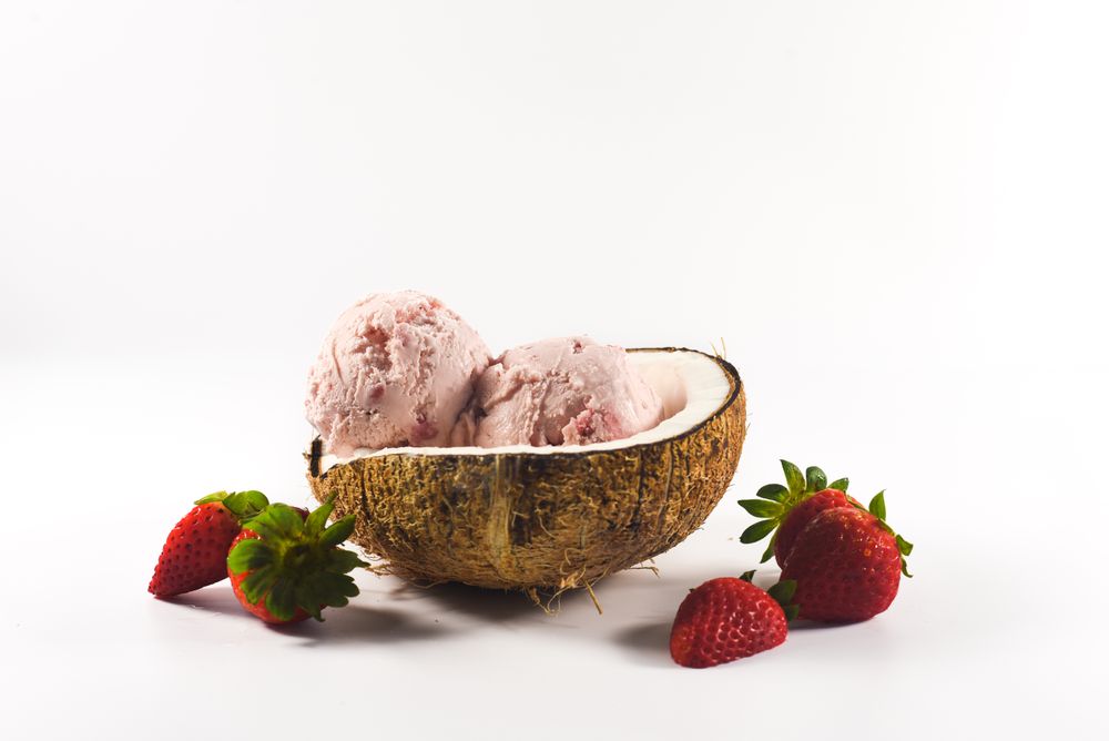Side view of coconut shell with strawberry ice cream and fruit halves
