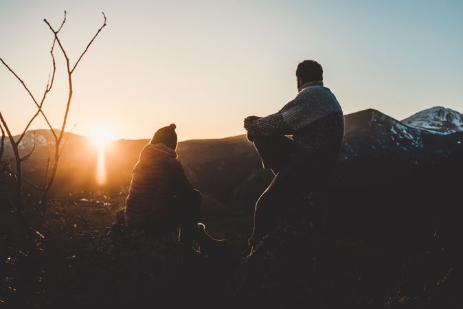 Man and woman enjoying sunset in autumn mountains