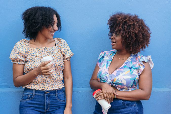 Two Women drinking coffee in the street, talking and laughing.