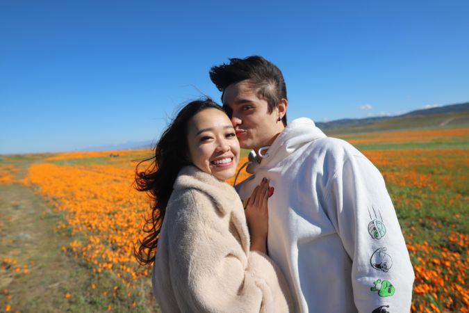 Man and woman hugging and standing on yellow flower field