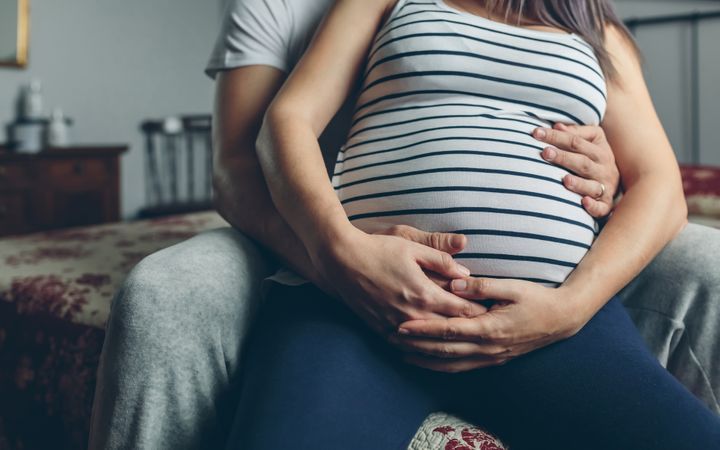Pregnant woman embraced by her husband