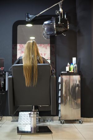Rear shot of female with long hair sitting in salon chair
