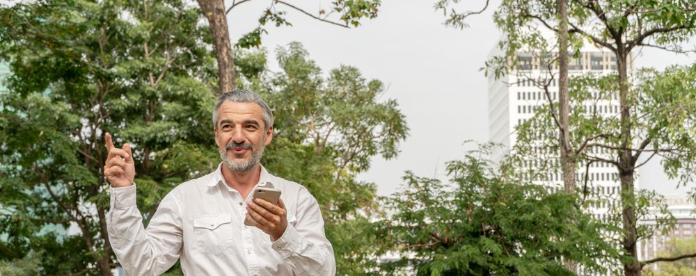 Mature grey haired man texting in park, banner