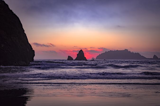 Looking out at rocks from the coast at sunset