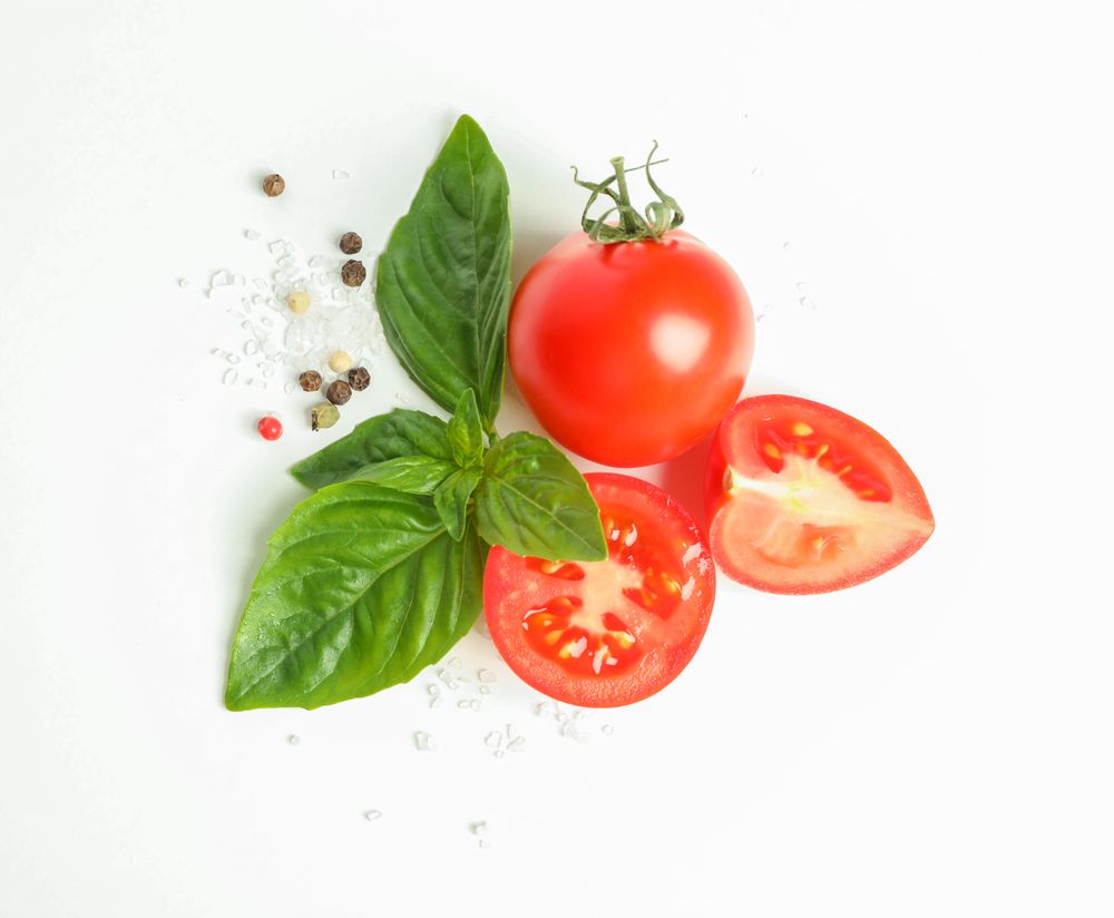 Fresh cherry tomatoes with basil and spices on blank background, space for text and top view. Ripe vegetables