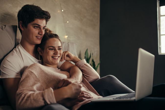 Loving couple with laptop on bed
