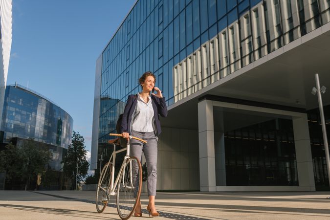 Cheerful manager with bicycle talking on smartphone