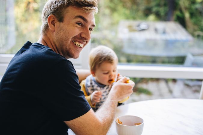Smiling man feeding baby with spoon