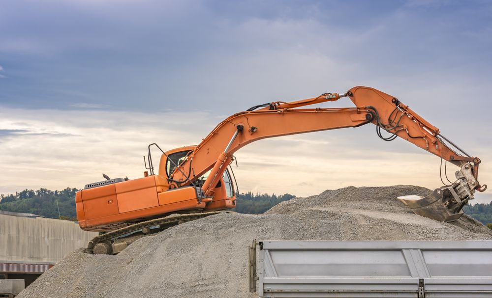 Excavator loading ballast in a trailer