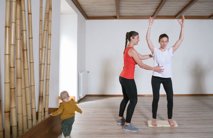 Trainer helping mother with exercise