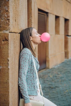 Side view of woman blowing bubble gum