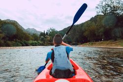 Female kayaking with paddle in raised hands