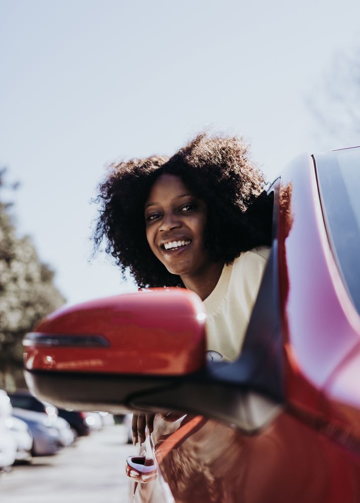 Black female with afro hair peeking out of the car .