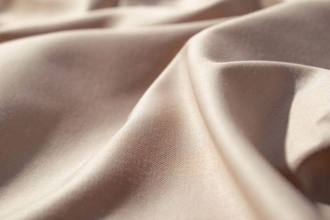 Close up silk shiny light brown fabric background texture.