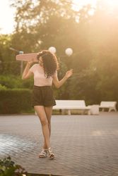 Teenager with pink skateboard behind her head