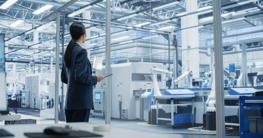 Electronics Manufacturing Technician Working on Tablet Computer at a Factory Space. Asian Female Specialist Developing, Maintaining, and Fine Tuning Programs for Machine Production and Assembly
