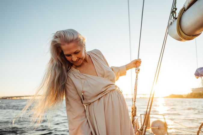 Older woman looking down on a yacht at sunset