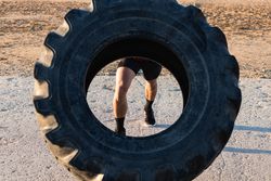 Anonymous strong man doing tire flip exercise