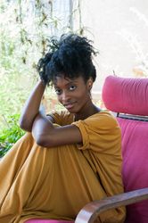 Woman with curly bun looking at camera confidently while sitting outside