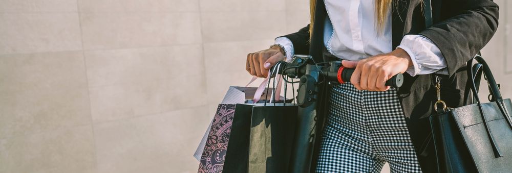 Unrecognizable woman with shopping bags on electric scooter