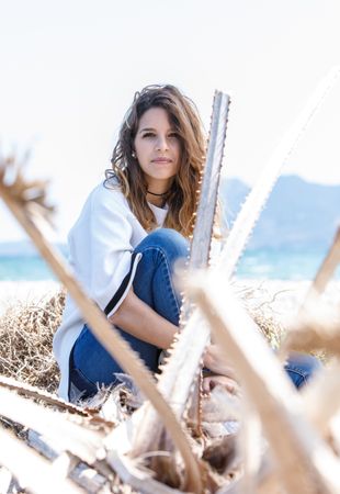 Young woman sitting near dried plants