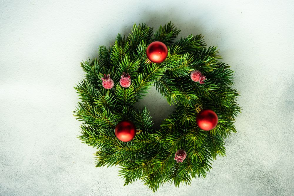 Christmas wreath with red baubles and berries on marble counter