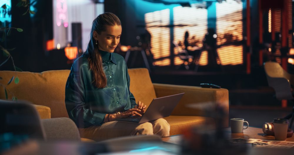 Portrait of White Creative Young Woman Working on a Laptop in Creative Office at Night.
