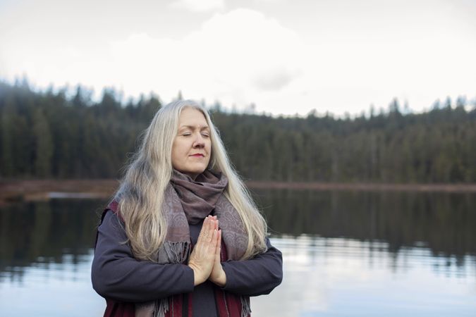 Female in namaste prayer pose on lake