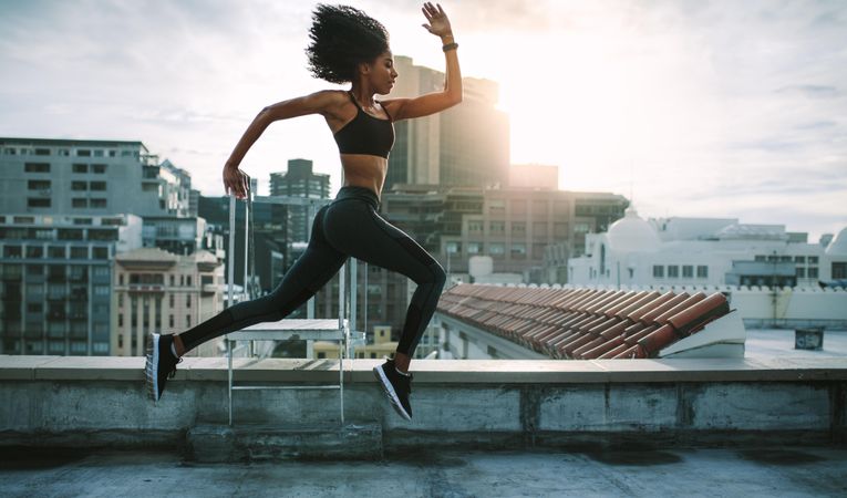 Woman in fitness wear training on terrace of a building