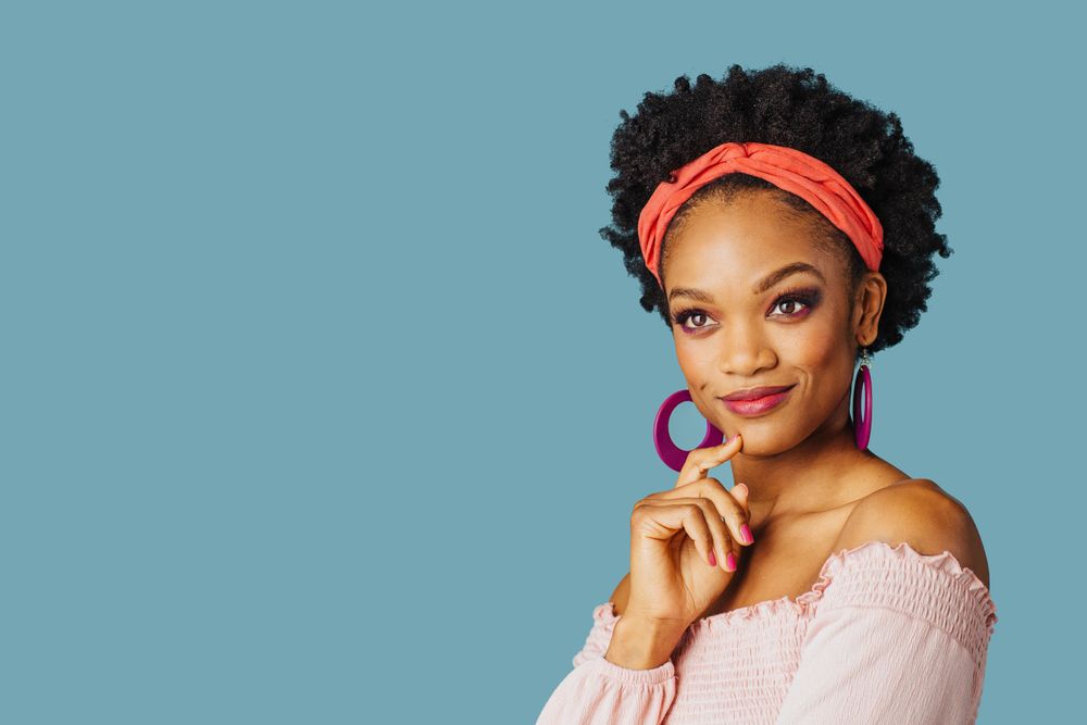 Studio shoot of smiling Black woman with hand on her chin