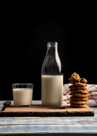 Milk and fresh cookies on board near napkin