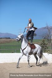 Man in checkered shirt standing up on saddle while riding horse beXr9N