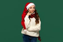 Girl in Santa hat thinking while posing for Christmas.