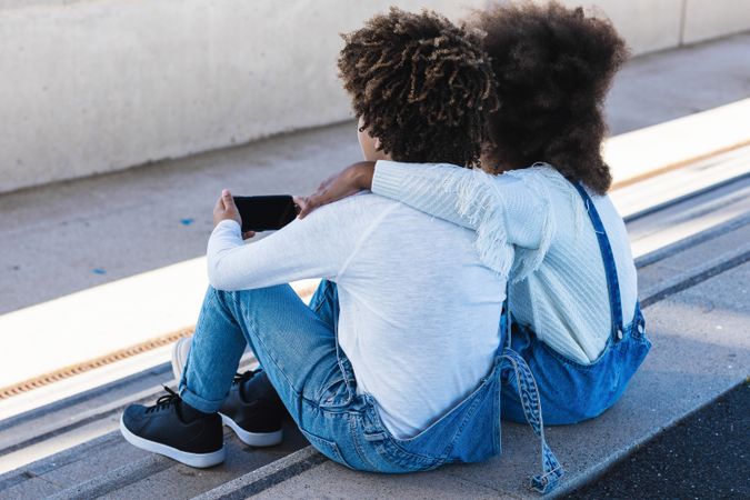 Black kids using smartphone together on street