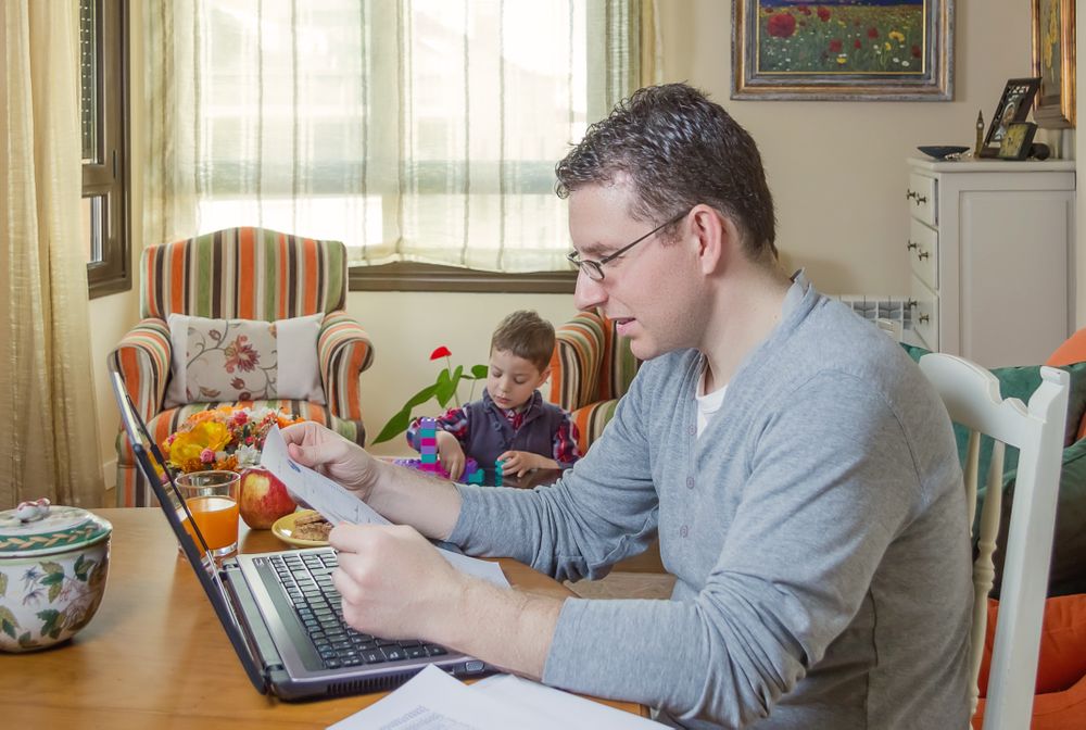Father working in home office and son playing