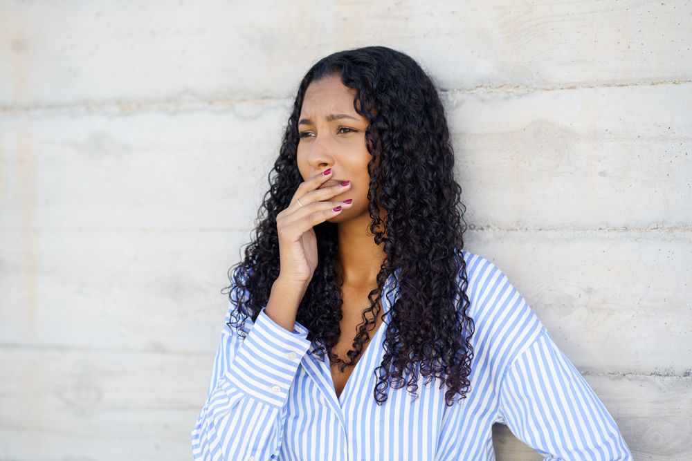 Contemplative young woman sporting curly hair and dressed in casual attire, deep in thought