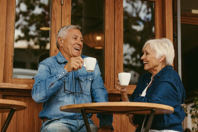Portrait of older couple sitting at table and drinking coffee in cafe ouside