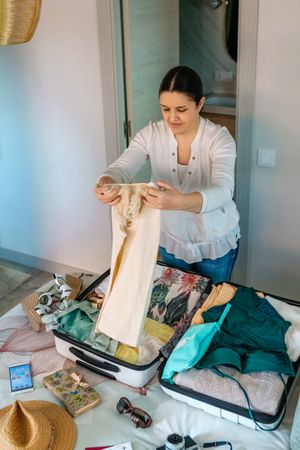 Woman preparing suitcase for summer vacations