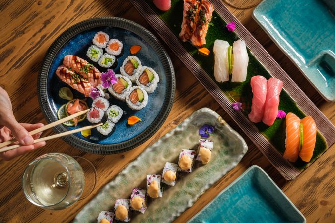 Person taking maki sushi roll from plate
