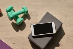 Smartphone placed near dumbbells on floor