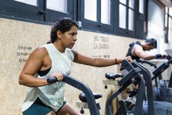 Determined Hispanic sportswoman exercising on air bike