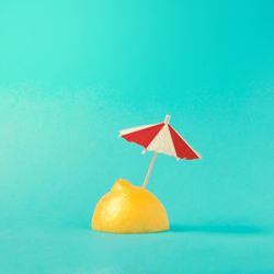 Lemon half with parasol on bright blue background